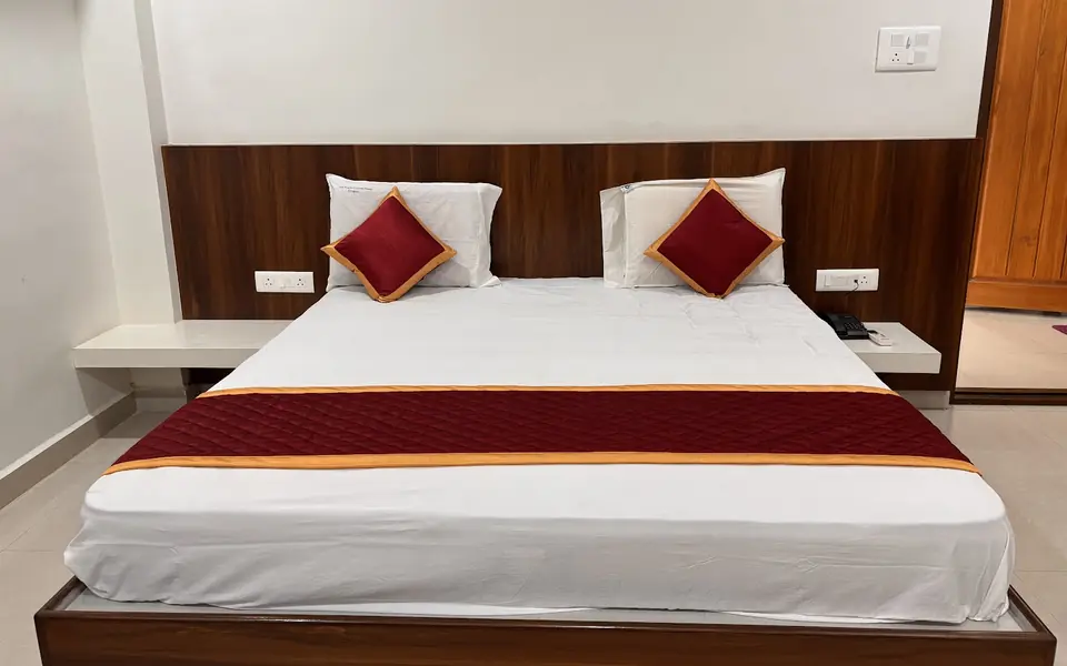 Executive Room bed with warm wood panelling at Arcade Stay Inn, Tirupati