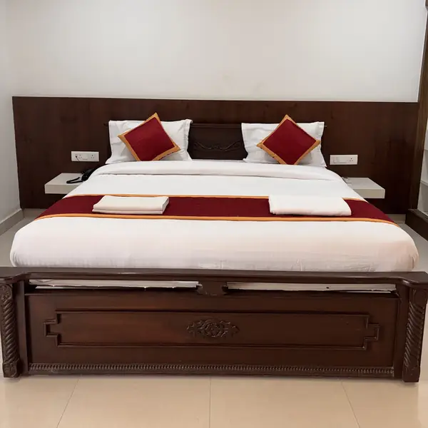 Delux Room bed with wooden headboard and storage